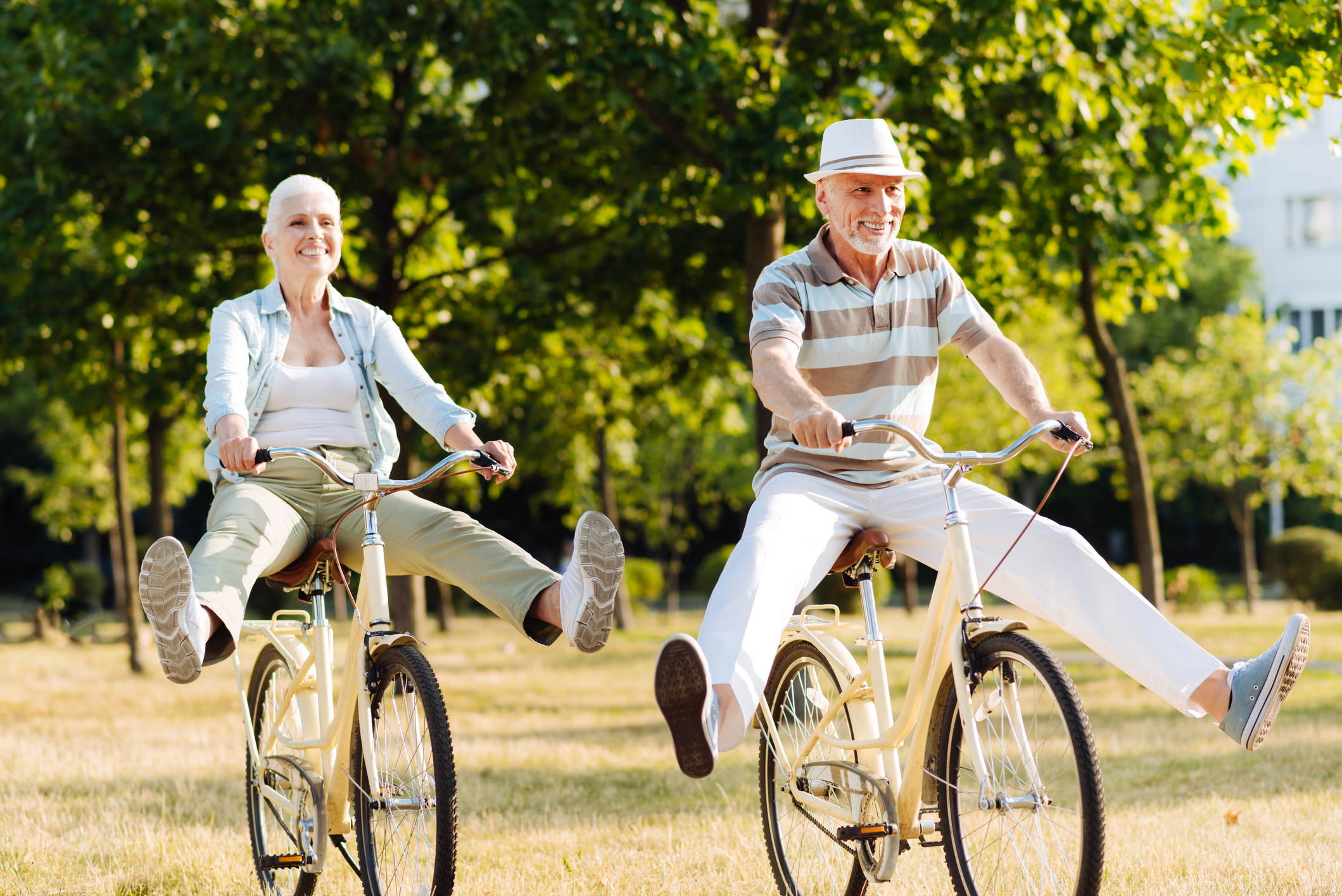 Photo of two older adults playfully riding bicycles